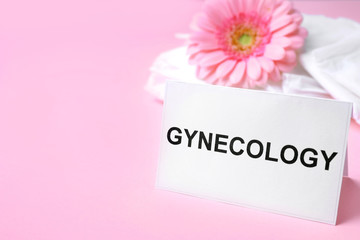 Card with word Gynecology, packed menstrual pads and flower on color background. Space for text