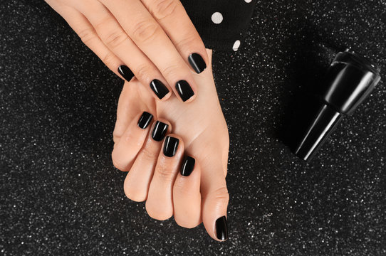 Woman With Black Manicure And Nail Polish Bottle On Dark Background, Top View