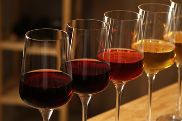 Glasses of different wines against blurred background, closeup. Expensive collection