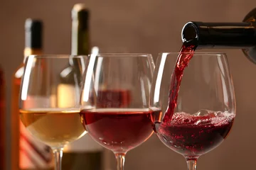 Fototapeten Pouring wine from bottle into glass on blurred background, closeup © New Africa
