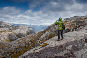 Woman tourist makes mobile photo of Beautiful nature landscape in Norway on the phone. Mountains and sky above the lysefjord.