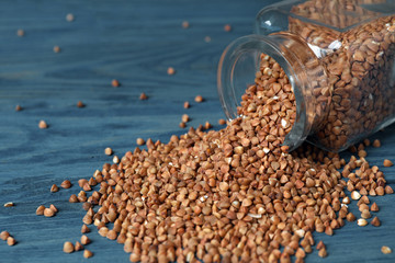Overturned glass jar with uncooked buckwheat on table