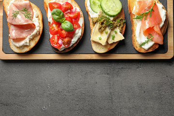 Board with different tasty bruschettas on grey table, flat lay. Space for text