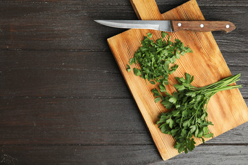 Board with fresh green parsley and knife on wooden background, top view. Space for text