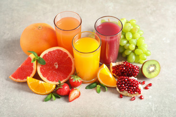 Glasses of different juices and fresh fruits on table