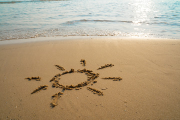 Vacation on the sand beach concept. The Sun symbol, sunshine drawing into the sand on the beach at Rayong, Thailand