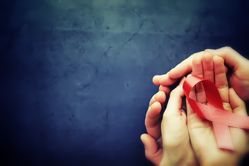 Symbol of human immunodeficiency virus disease. Red ribbon. A helping hand and support.