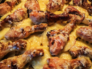 Baked chicken drumstick with cheese and potato closeup