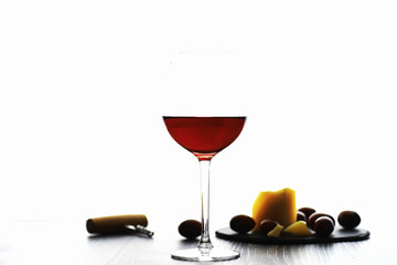 A glass of red dry wine on the table. Dark bottle and glass of wine.