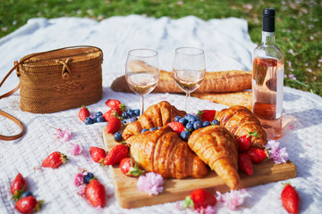 Beautiful picnic with rose wine, French croissants and fresh berries