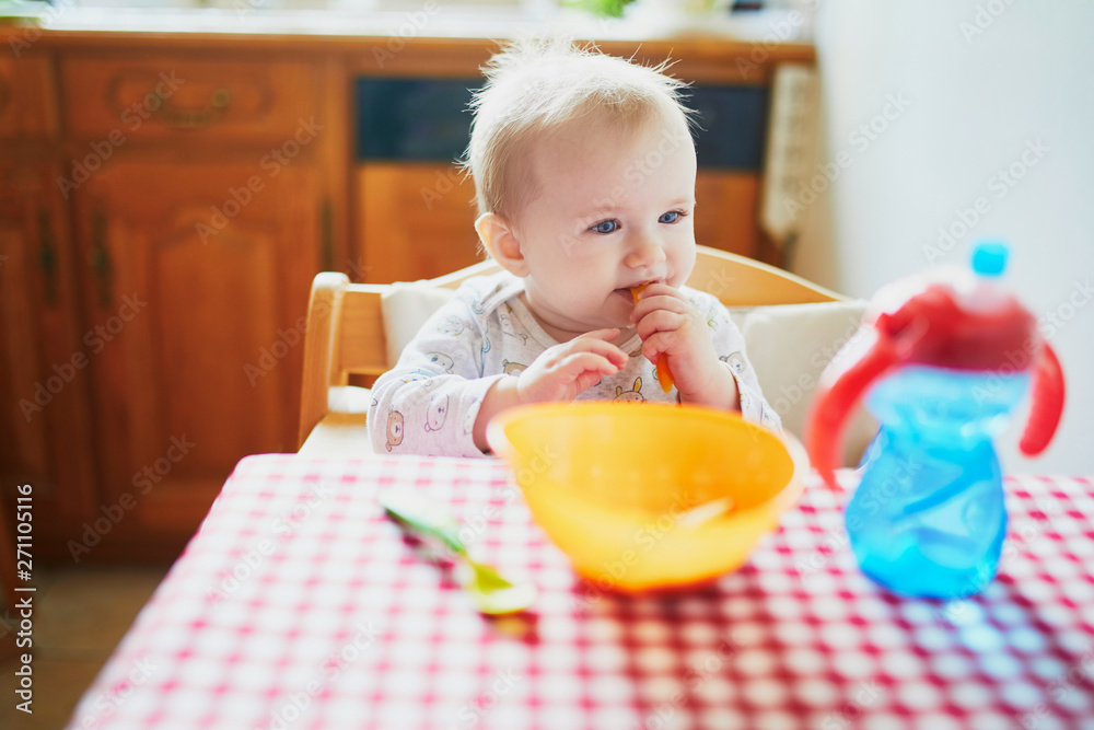 Wall mural Cute baby girl eating lunch in the kitchen