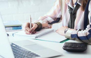 Side view of business woman making notes with silver pen in office background. Business finance savings loan and credit concept.