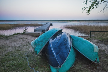 old rowing boats inverted on the shore on the background of the pier and lake