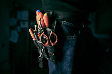 Detail of tools belt of electrician worker at home kitchen in low key screw, low key