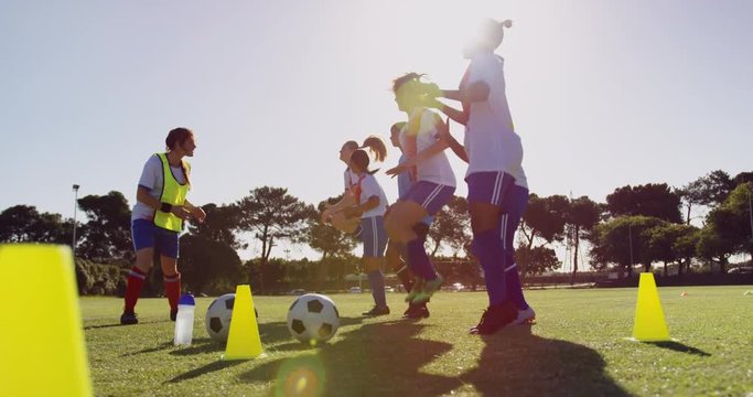 Female soccer players jumping on the place while captain gives training. 