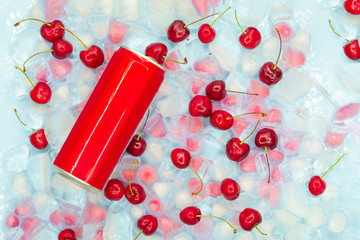 Refreshing drink in a metal can against a background of transparent and pink ice cubes with ripe...