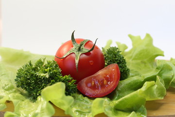 Red tomatoes with greenery on the wooden board