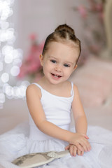 Beautiful small girl in white dress posing indoor.