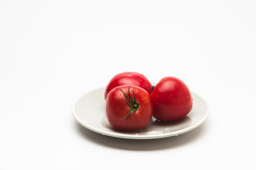  Red tomatoes in a plate on white background 