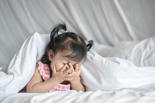 Closeup A Little Girl Take Her Hands Off The Face And Play Hidden With Someone On Bed Under Blanket In Bedroom Background