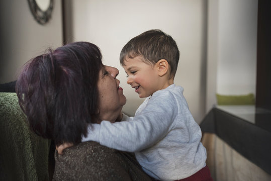 Grandmother and grandson indoors image. Hug in living room.