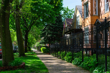 Obraz premium Sidewalk next to a Row of Old Fenced in Homes in Logan Square Chicago