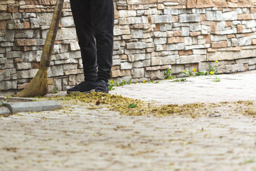 Worker sweeping the pavement with broom. Street sweeper cleaning footpath in the city park