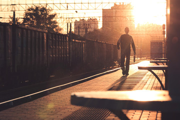Man walking along the train station at sunset