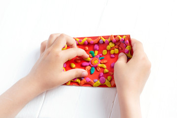 The child sculpts from plasticine a bright multi-colored rug. Tutoring with children