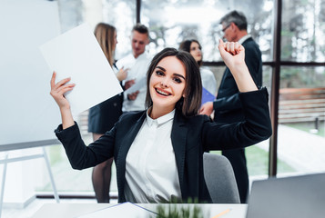 happy young business woman celebrating and looks up with hands in the air with papers on hands.. © Тарас Нагирняк