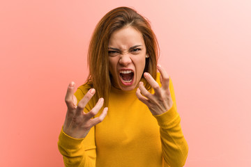 Young pretty young woman upset screaming with tense hands.