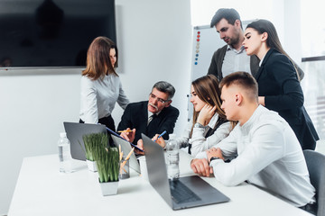 Young business people typing on a laptop and writing at the modern office space.