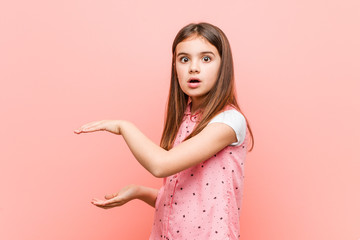 Cute little girl shocked and amazed holding a copy space between hands.