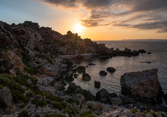 A beach full of fallen boulder during sunset
