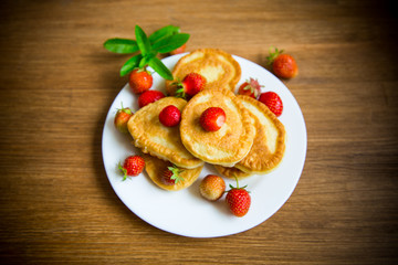 fried sweet pancakes with ripe strawberries in a plate