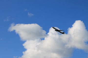 Flying plane in the blue sky with clouds