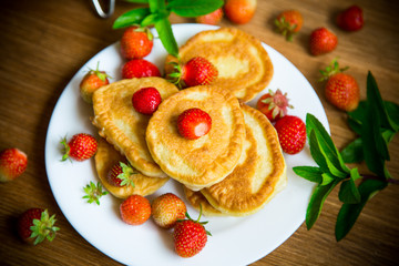 fried sweet pancakes with ripe strawberries in a plate