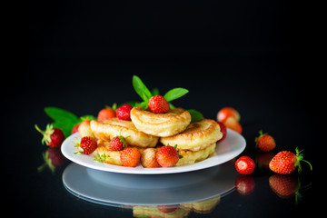 fried sweet pancakes with ripe strawberries in a plate