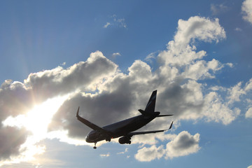 Flying plane in the blue sky with clouds