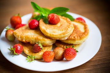 fried sweet pancakes with ripe strawberries in a plate