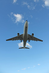 Flying plane in the blue sky with clouds