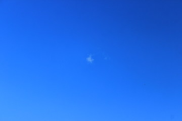 A small white cloud high in the sky. Blue sky.