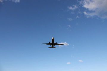 Flying plane in the blue sky with clouds