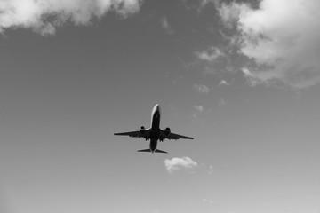 Flying plane in the blue sky with clouds