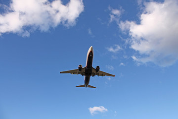 Flying plane in the blue sky with clouds