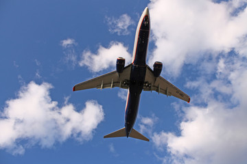 Flying plane in the blue sky with clouds