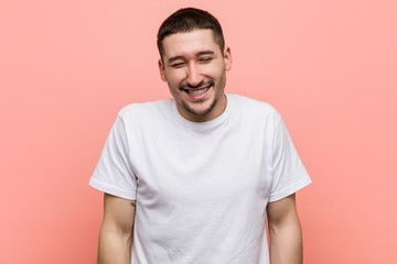 Young casual man laughs and closes eyes, feels relaxed and happy.