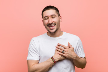 Young casual man laughing keeping hands on heart, concept of happiness.