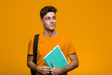 Young student man holding books biting fingernails, nervous and very anxious.