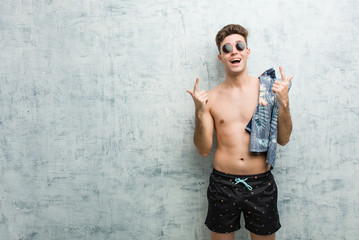 Young caucasian man wearing a swimsuit indicates with both fore fingers up showing a blank space.